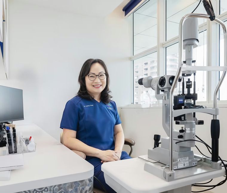 Dr Audrey Pang seated beside a slit lamp in the clinic.
