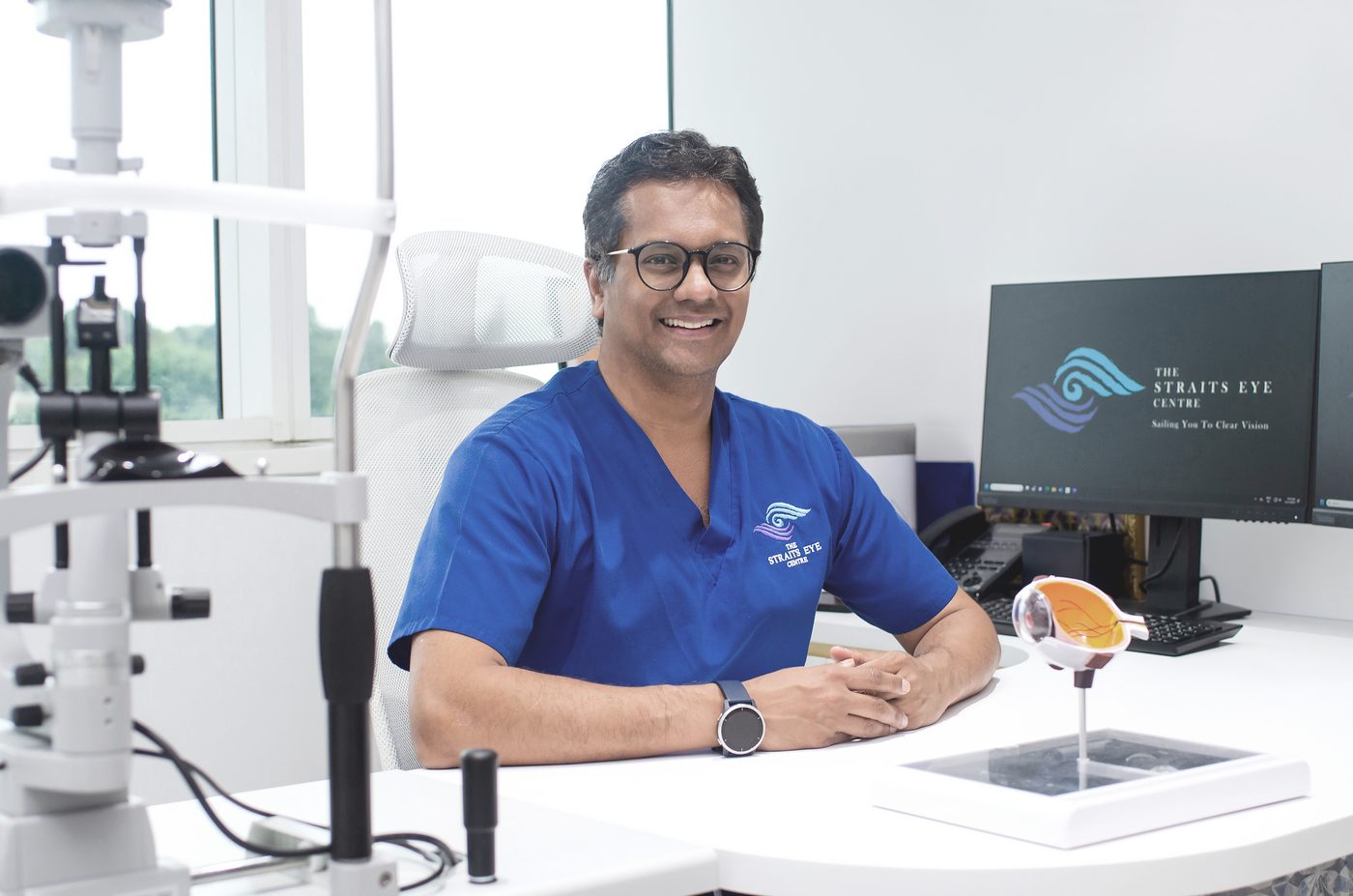 Dr Jayant V Iyer at a consultation desk at The Straits Eye Centre, with a slit lamp beside him.