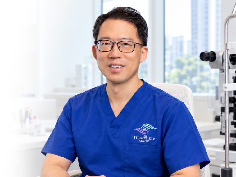 Dr Laurence Lim Shen in The Straits Eye Centre scrubs, seated at a slit lamp.