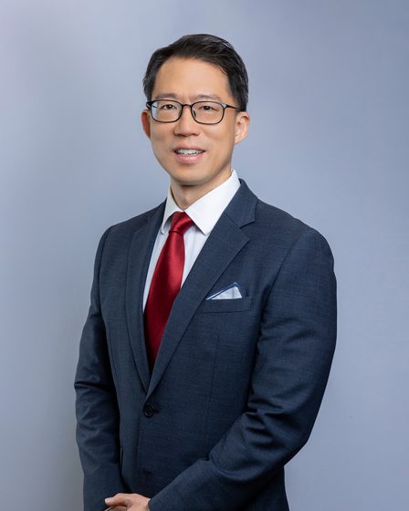 Dr Laurence Lim Shen in The Straits Eye Centre scrubs, seated at a slit lamp.