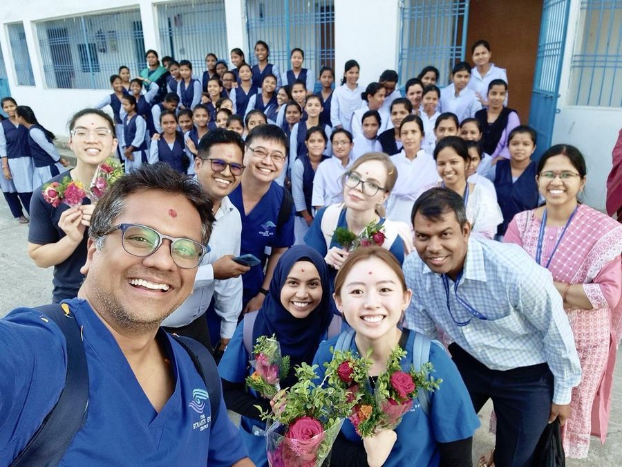 Dr Jayant V Iyer and colleagues in Straits Eye Centre scrubs with a large group of people in uniform during an overseas outreach visit.